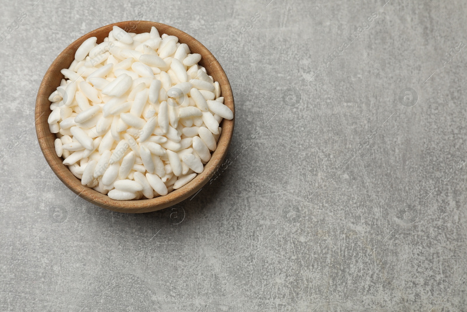 Photo of Puffed rice in bowl on light grey table, top view. Space for text