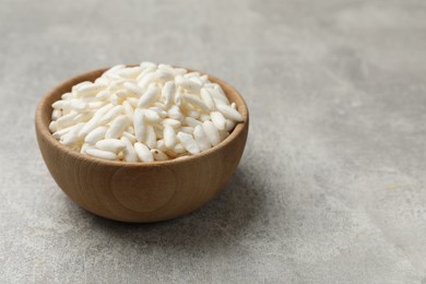 Photo of Puffed rice in bowl on light grey table, closeup. Space for text