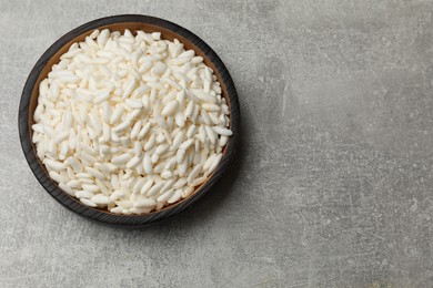 Photo of Puffed rice in bowl on light grey table, top view. Space for text