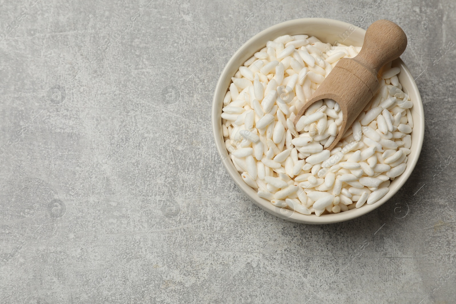 Photo of Puffed rice in bowl and scoop on light grey table, top view. Space for text