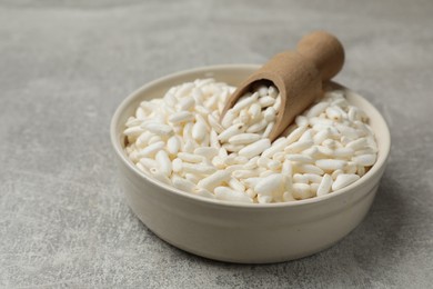 Photo of Puffed rice in bowl and scoop on light grey table, closeup