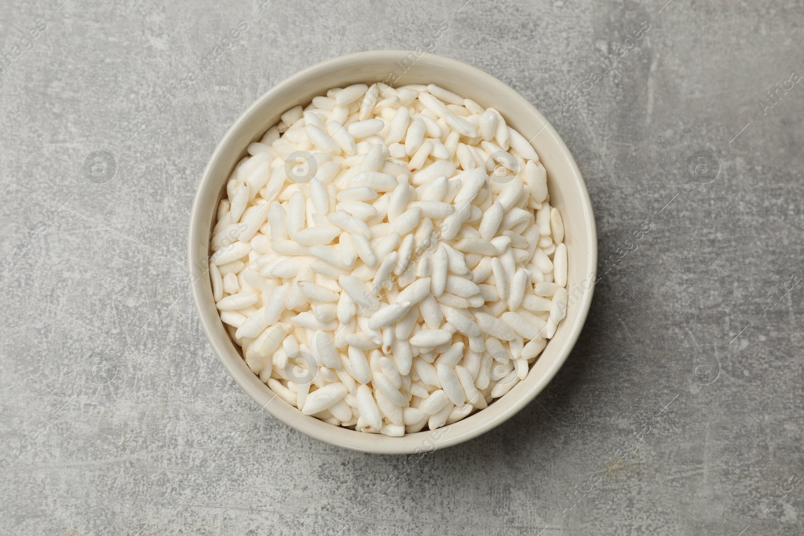 Photo of Puffed rice in bowl on light grey table, top view