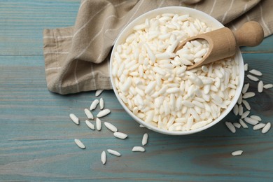 Photo of Puffed rice in bowl and scoop on light blue wooden table, flat lay