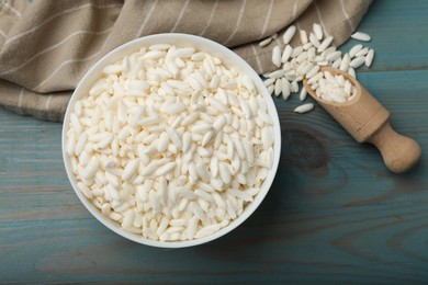 Photo of Puffed rice in bowl and scoop on light blue wooden table, flat lay