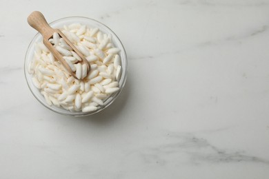 Photo of Puffed rice in bowl and scoop on white marble table, top view. Space for text