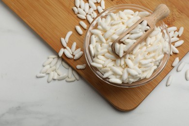 Photo of Puffed rice in bowl and scoop on white marble table, top view