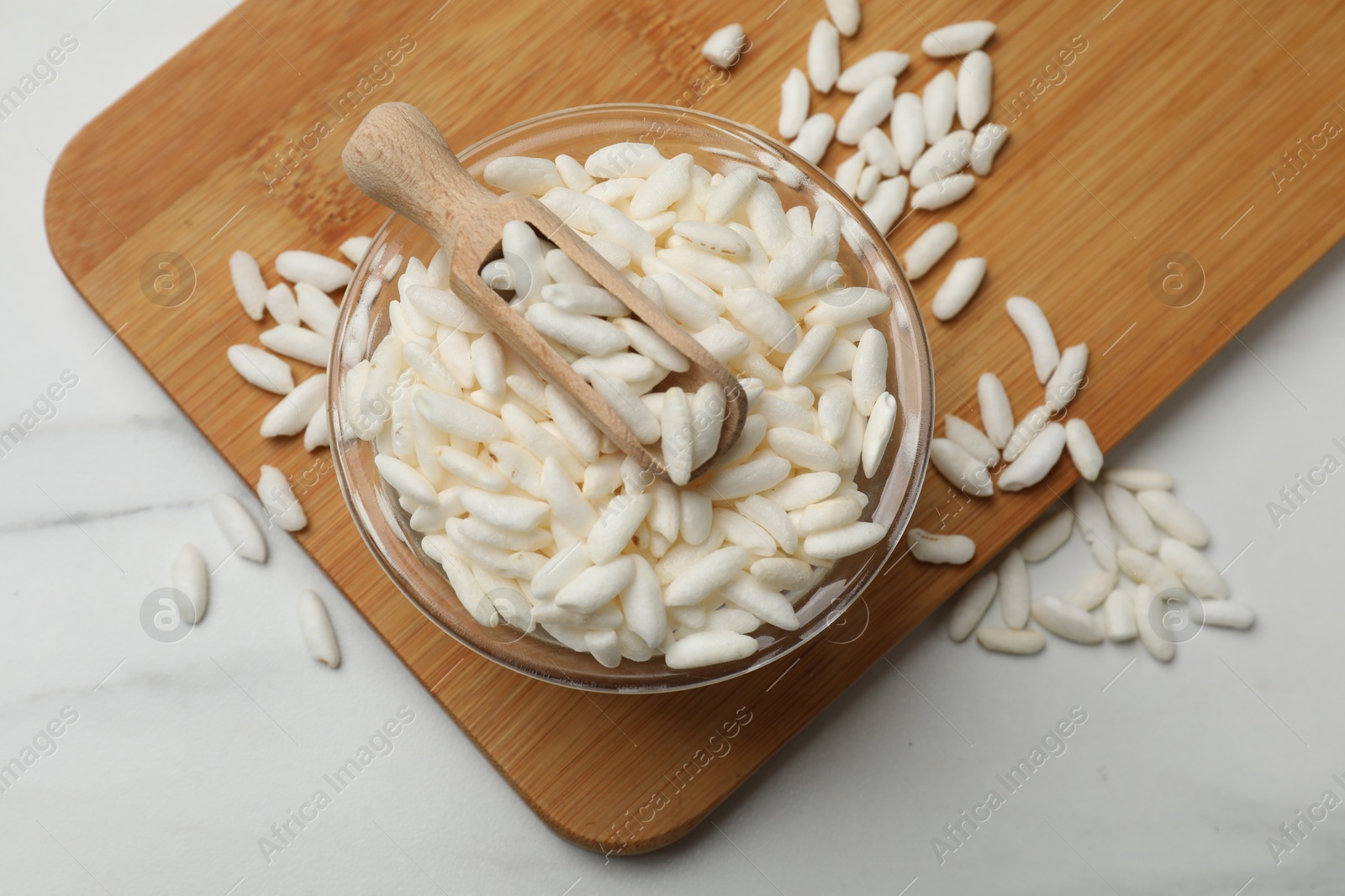 Photo of Puffed rice in bowl and scoop on white marble table, top view