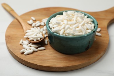 Photo of Puffed rice in bowl and spoon on white table, closeup