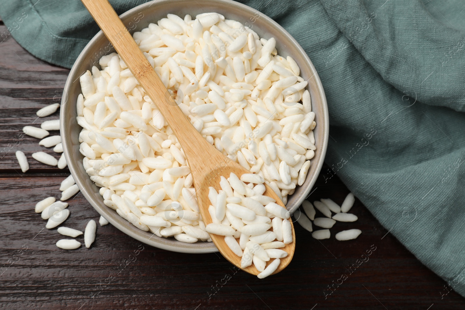 Photo of Puffed rice in bowl and spoon on wooden table, top view