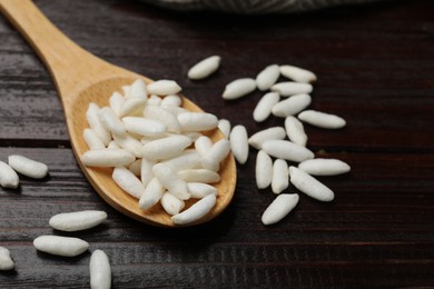 Photo of Puffed rice in spoon on wooden table, closeup