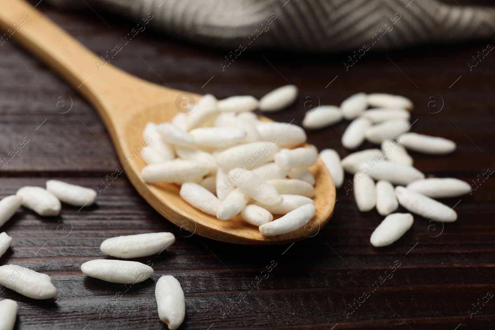 Photo of Puffed rice in spoon on wooden table, closeup