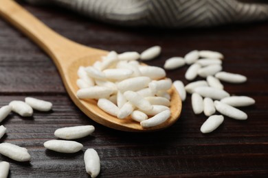 Photo of Puffed rice in spoon on wooden table, closeup