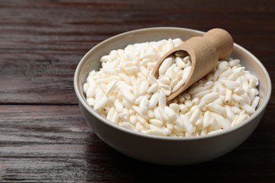 Photo of Puffed rice in bowl and scoop on wooden table, closeup