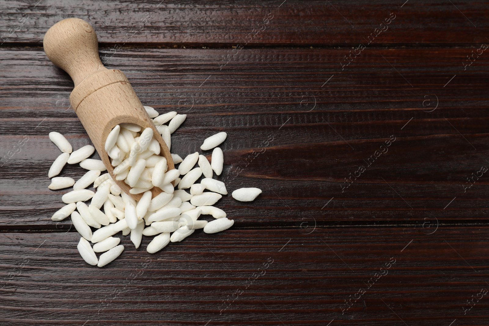 Photo of Puffed rice in scoop on wooden table, top view. Space for text