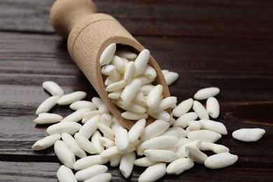 Photo of Puffed rice in scoop on wooden table, closeup