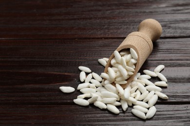 Photo of Puffed rice in scoop on wooden table, closeup. Space for text