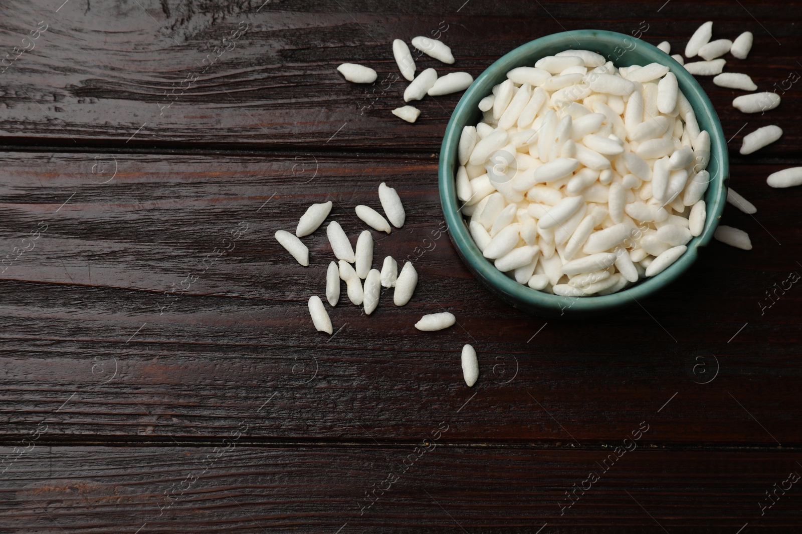 Photo of Puffed rice in bowl on wooden table, top view. Space for text