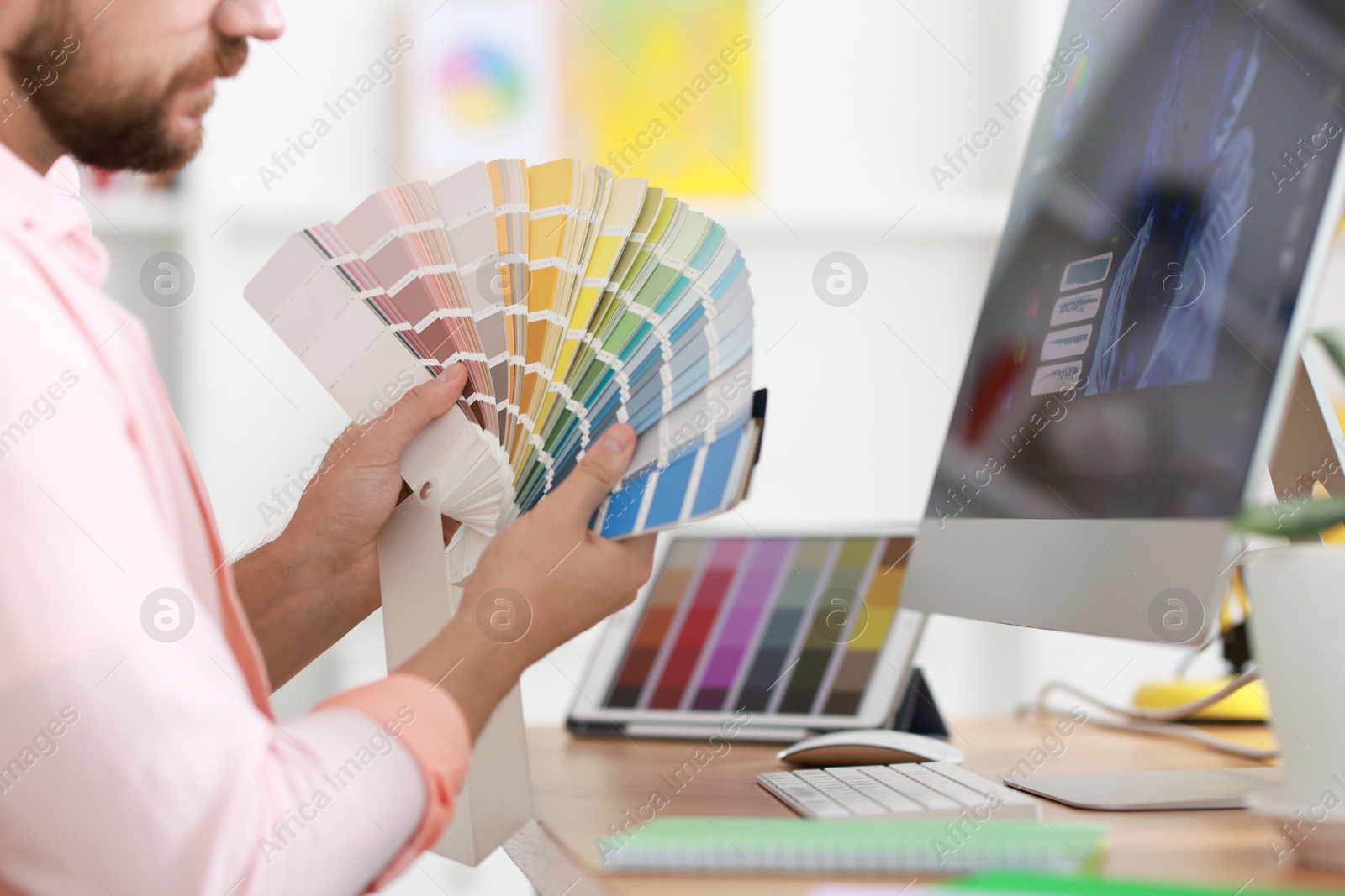 Photo of Designer working with color samples at table in office, closeup