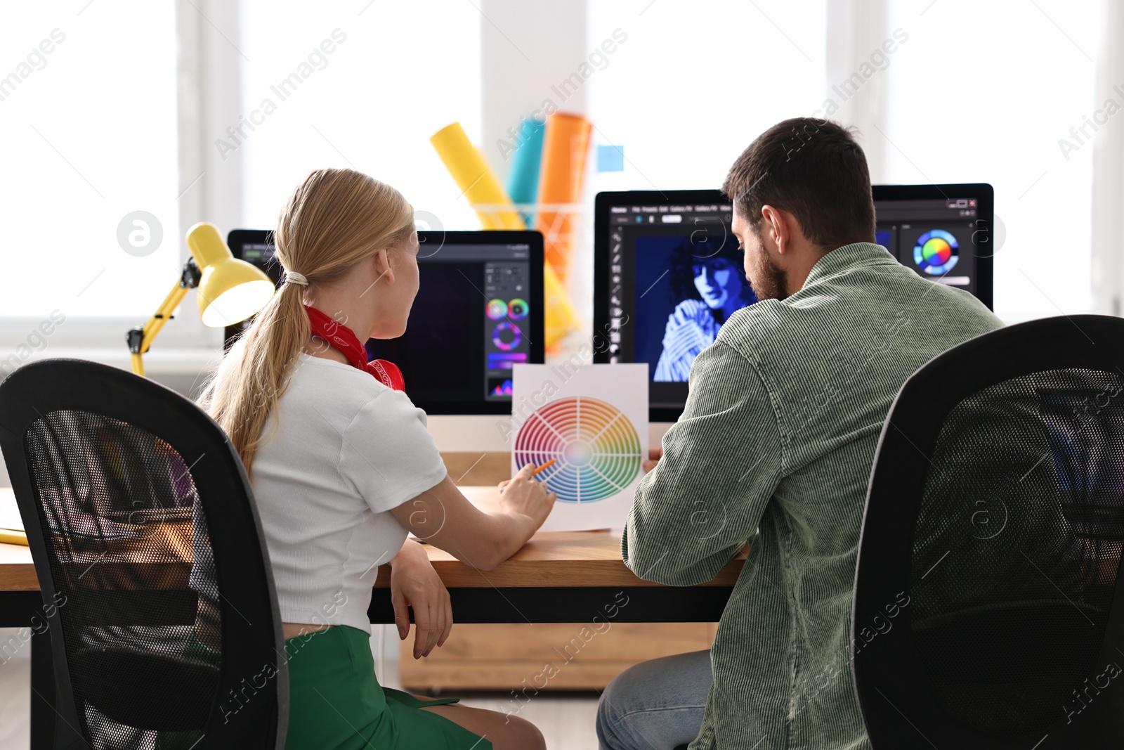 Photo of Designers with color palette working together at table in office, back view