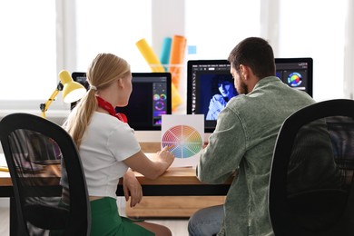 Designers with color palette working together at table in office, back view