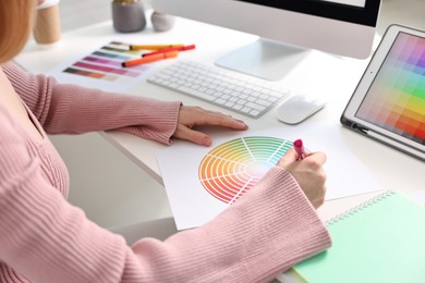 Photo of Designer working with color palette at table in office, closeup