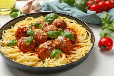 Delicious pasta with meatballs and ingredients on white marble table, closeup