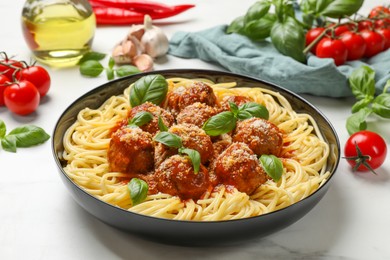 Photo of Delicious pasta with meatballs and ingredients on white marble table, closeup