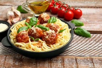 Photo of Delicious pasta with meatballs and ingredients on wooden table, closeup