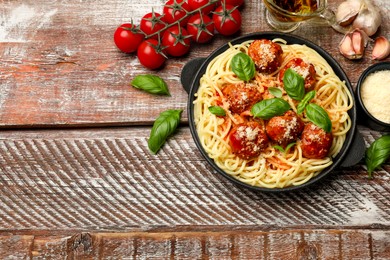 Delicious pasta with meatballs and ingredients on wooden table, flat lay. Space for text