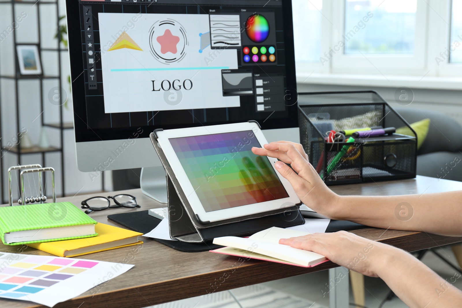 Photo of Designer working on tablet at wooden table indoors, closeup