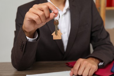 Photo of Real estate agent with house key at table, closeup