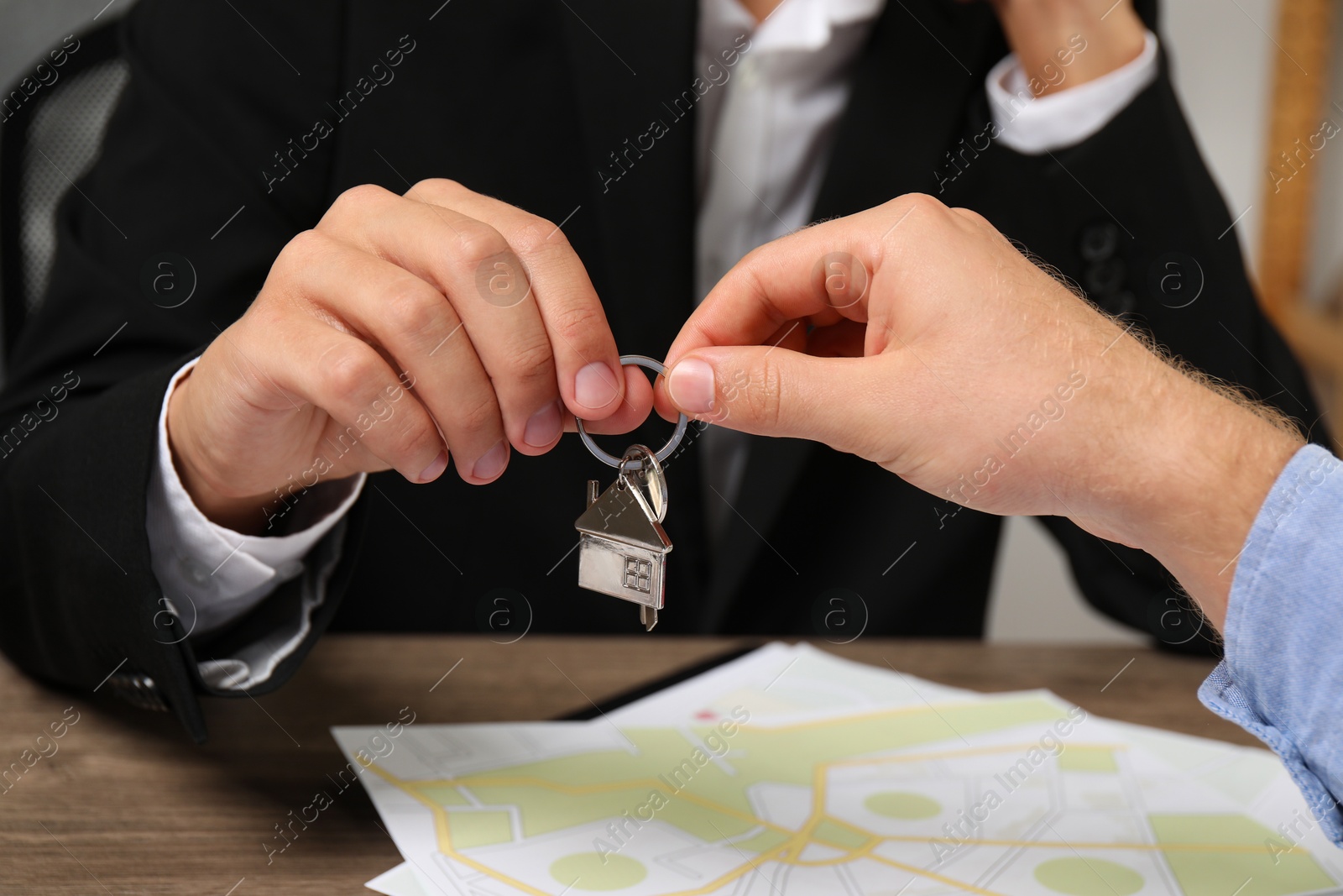 Photo of Real estate agent giving house key to new owner at table, closeup