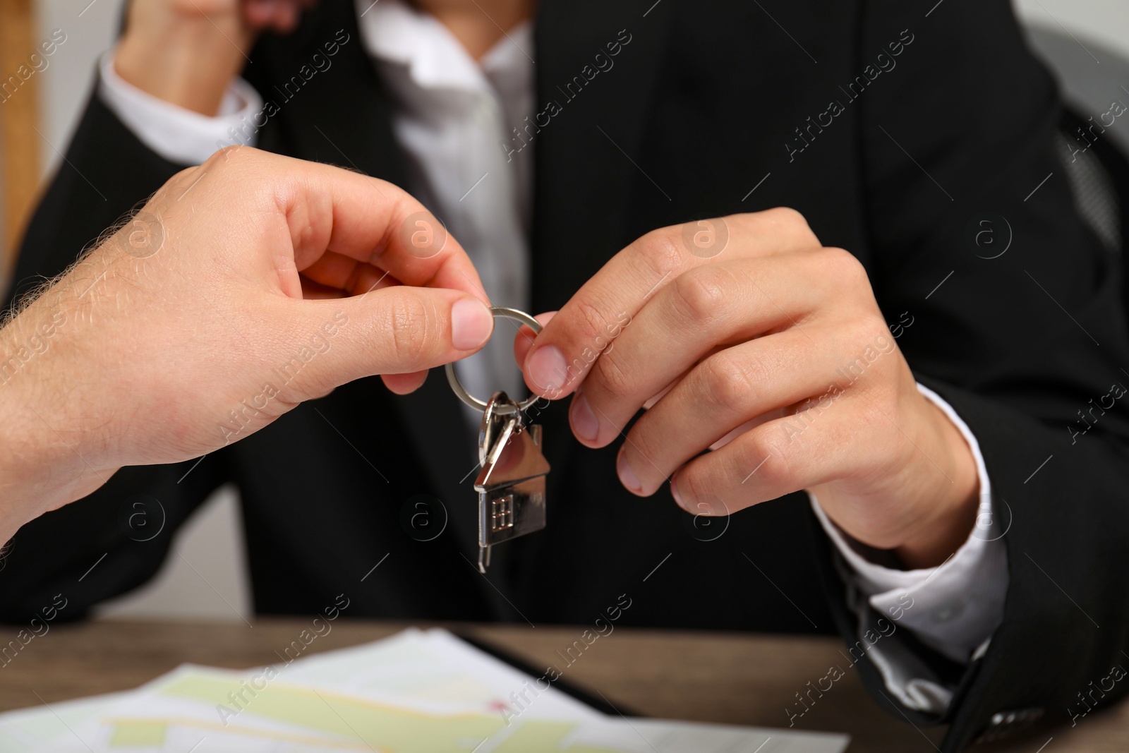 Photo of Real estate agent giving house key to new owner at table, closeup