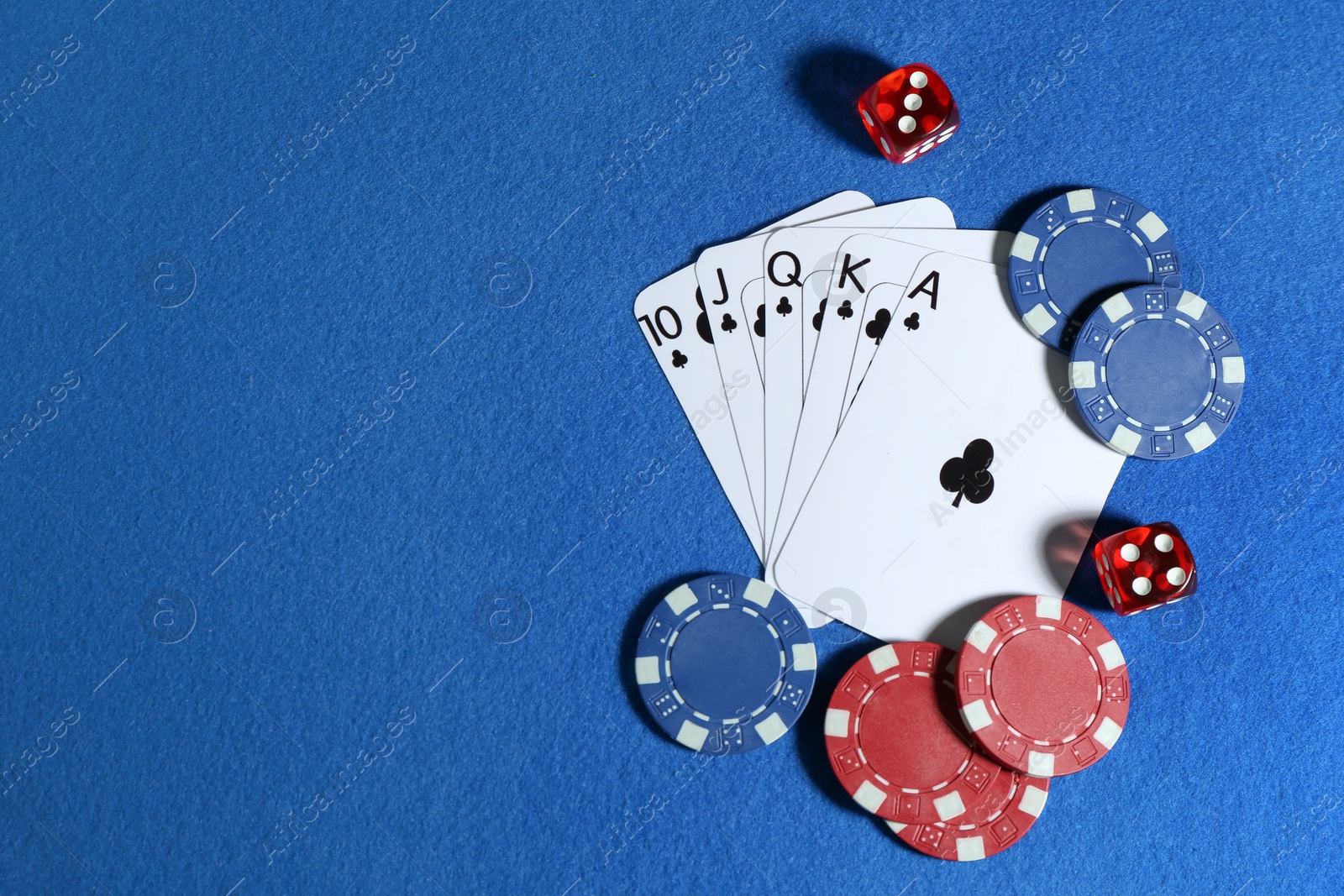 Photo of Playing cards, poker chips and cubes on blue table, flat lay. Space for text