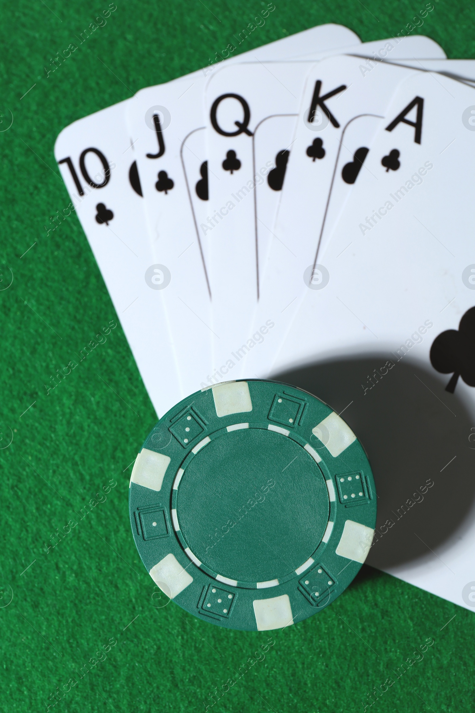 Photo of Playing cards and poker chips on green table, top view