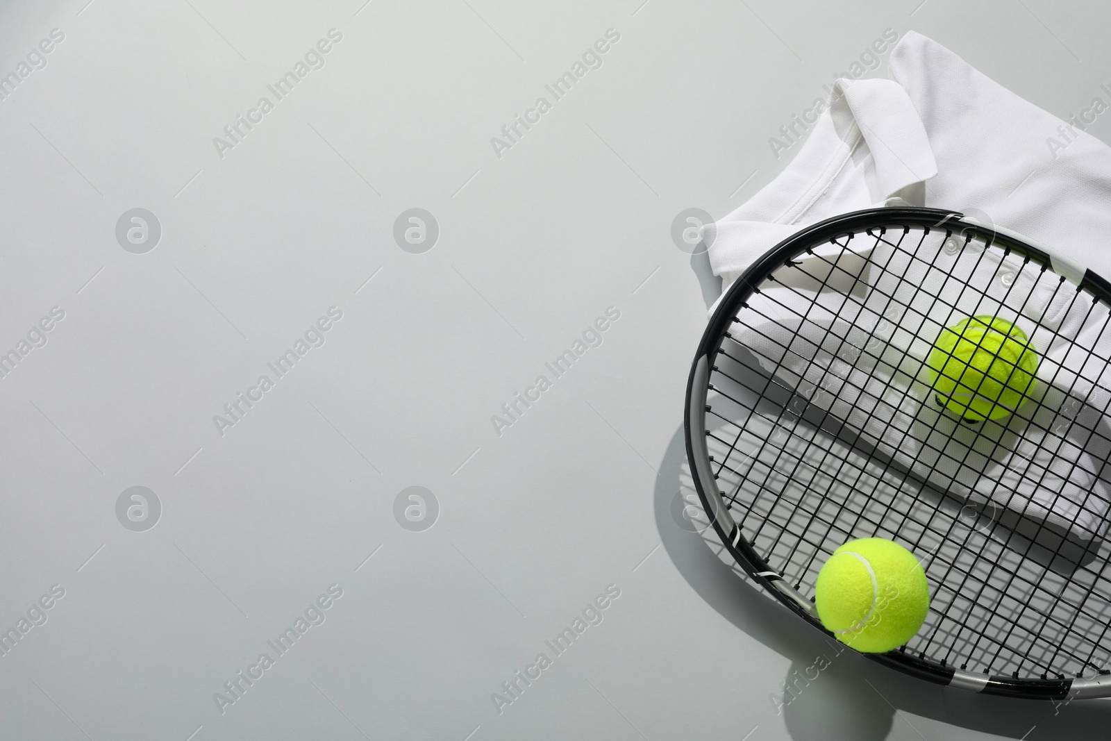 Photo of Tennis racket, balls and sportswear on light grey background, flat lay. Space for text