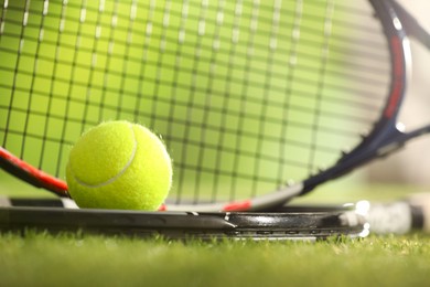 Photo of Tennis rackets and ball on green artificial grass, closeup