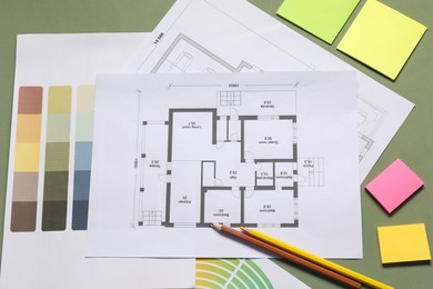 Photo of Designer's workplace with house plans, color palettes and stationery on green table, flat lay