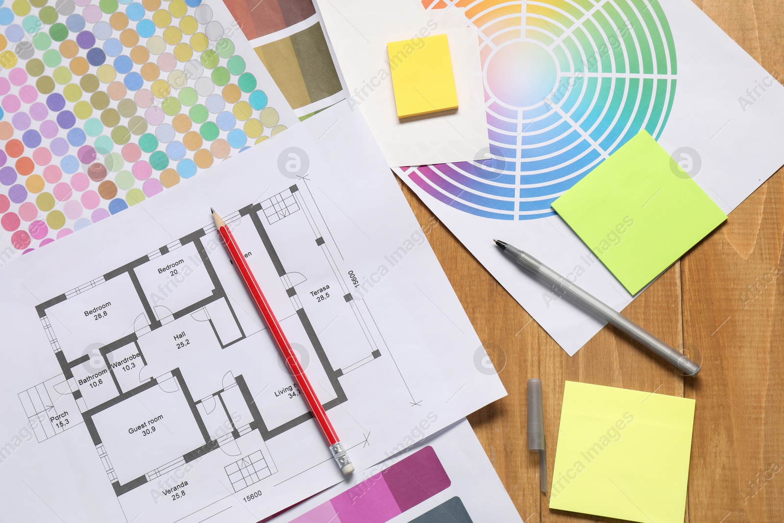 Photo of Designer's workplace with house plan, color palettes and stationery on wooden table, flat lay