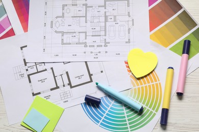 Photo of Designer's workplace with house plans, color palettes and stationery on light wooden table, flat lay