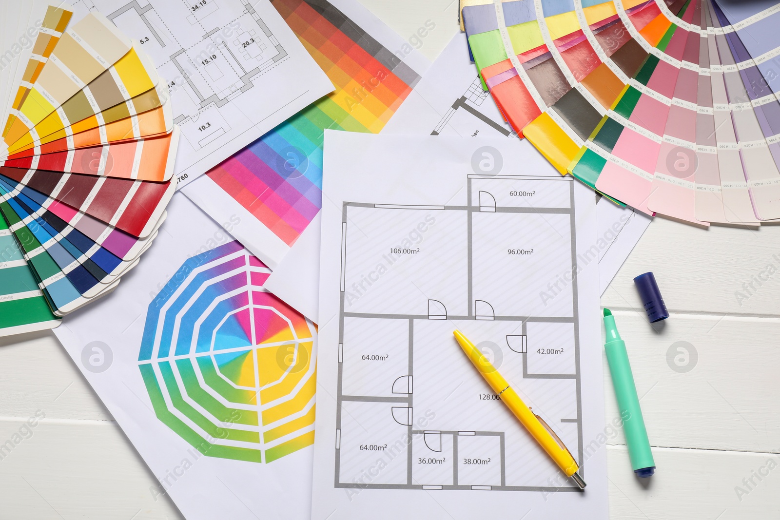 Photo of Designer's workplace with color palettes, floor plans and stationery on white wooden table, flat lay