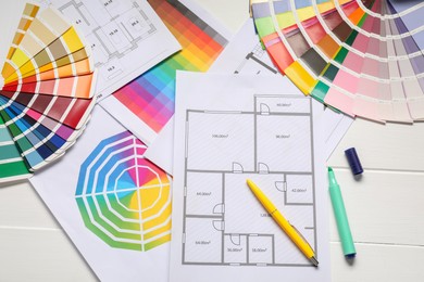 Photo of Designer's workplace with color palettes, floor plans and stationery on white wooden table, flat lay