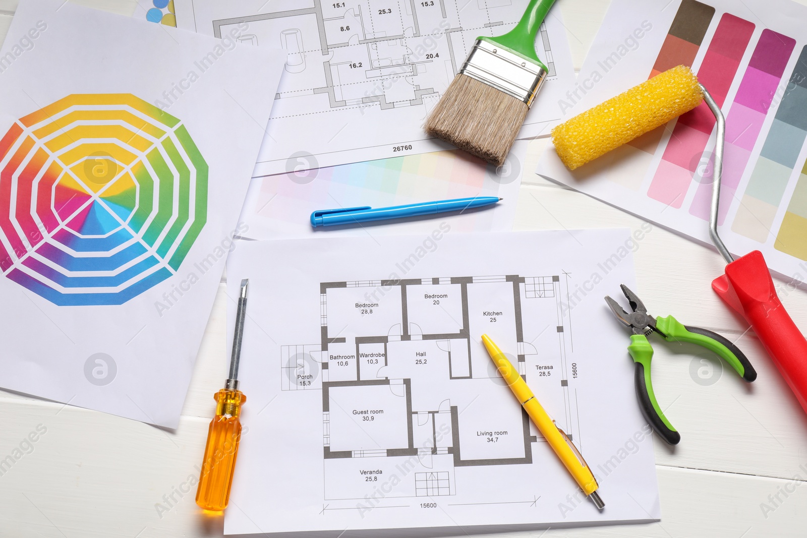 Photo of Designer's workplace with color palettes, floor plans and different supplies on white wooden table, flat lay