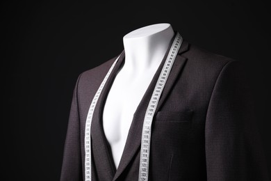 Photo of Male mannequin with jacket and measuring tape on black background, closeup