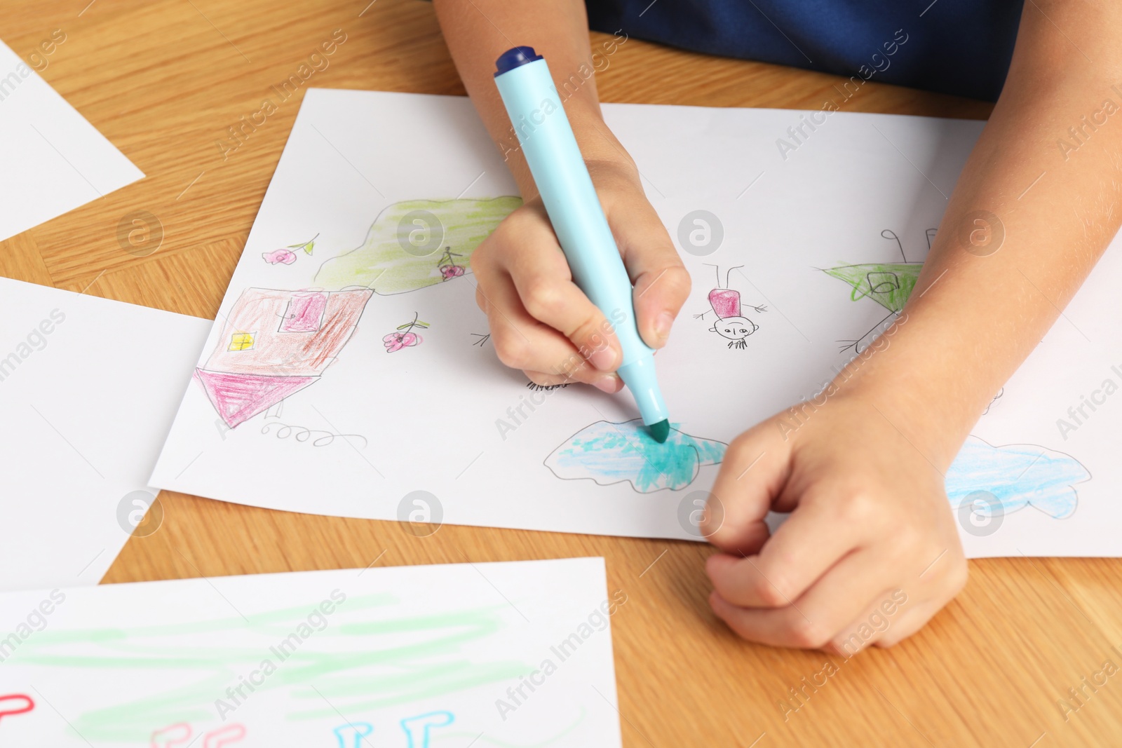 Photo of Boy drawing picture at wooden table, closeup