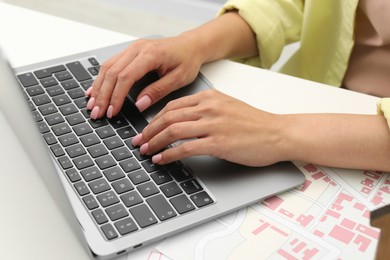 Photo of House hunting. Woman with laptop and papers at white table, closeup