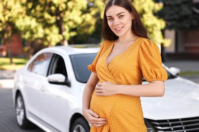 Portrait of smiling pregnant woman near car outdoors