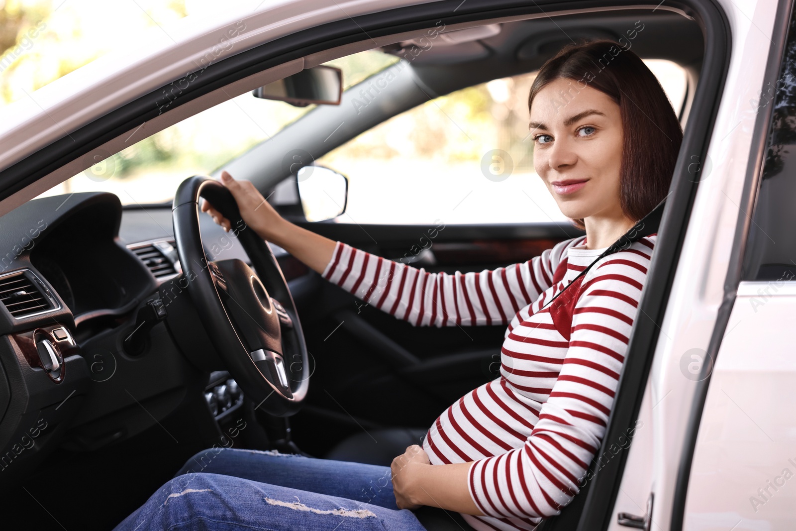 Photo of Pregnant woman with safety belt driving car, view from outside