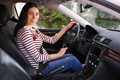 Photo of Smiling pregnant woman with safety belt driving car