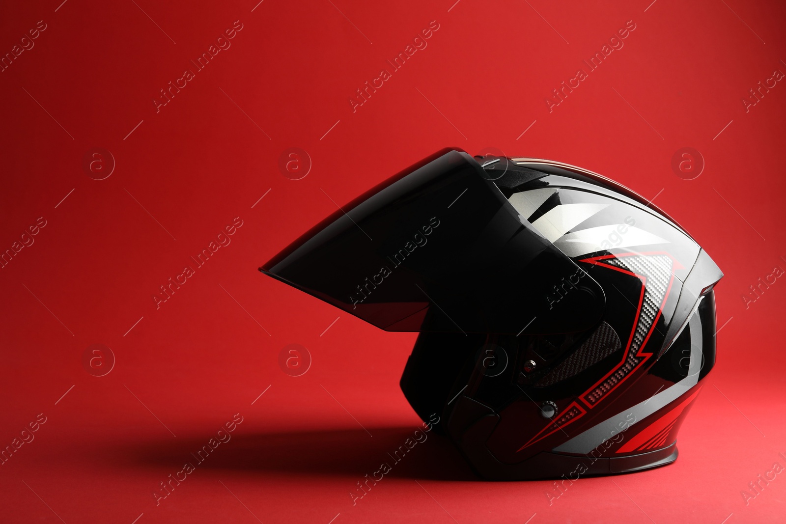 Photo of Modern motorcycle helmet with visor on red background, space for text